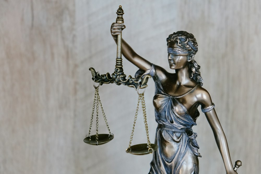 Bronze Lady Justice sculpture representing impartial legal representation and statutory compliance